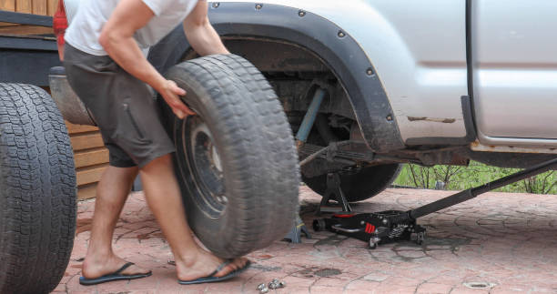 istock Young man changes tire on truck at home 1324910030