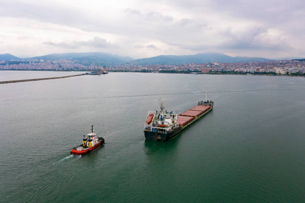 luftaufnahme des frachtschiffs, das sich mit schleppert nähert. - piloting commercial dock harbor industrial ship stock-fotos und bilder