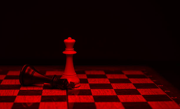 istock chess piece, white queen beats black king, on board, with red tones 1324916920