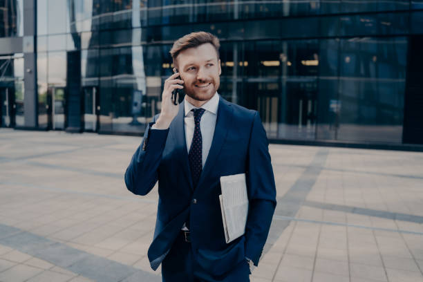 istock Happy office worker with newspaper talking on smartphone 1324918181