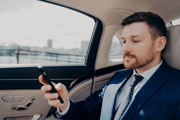 istock Investor checking his phone while riding in limousine 1324918210