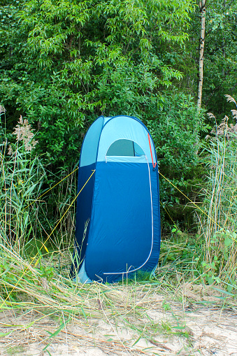 blue high tent without bottom, camp toilet or changing room, Camping shower. Camping travel hiking concept.