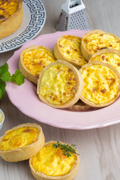istock cheese lorraine quiches on a pink plate, some cheese and mint decorative elements, wooden base, 1324923019