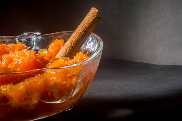pumpkin candy in an apple-shaped bowl with a cinnamon stick, black background and copy space