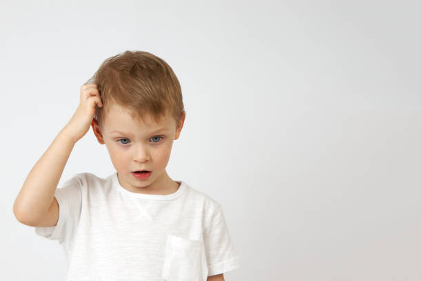 istock Little boy is deep in thought and scratching his head on a white background 1324929400
