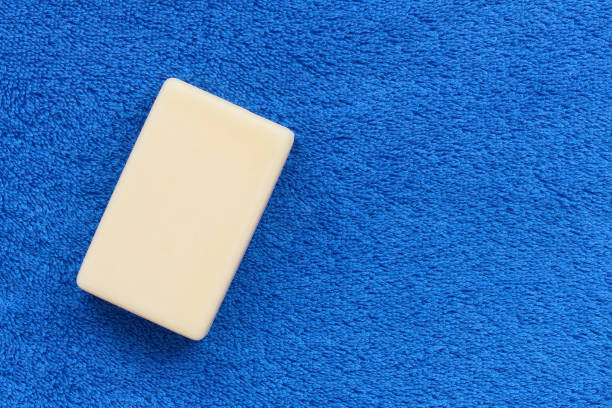White bar of soap on fluffy rustic towel blue with copy space, hygiene concept