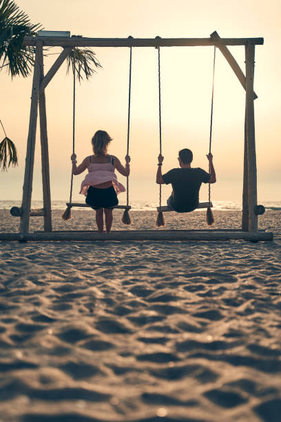 istock Young attractive couple swinging on seesaw on the beach. 1324930964