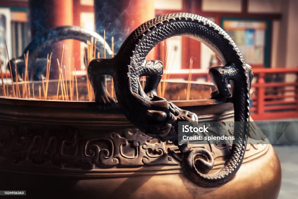 Dragon deity on worship bowl with candlestick in Asian Buddha Tooth Relic Temple in Singapore Dragon deity on worship bowl with candlestick in Asian Buddha Tooth Relic Temple in Singapore in Chinatown China - East Asia Stock Photo