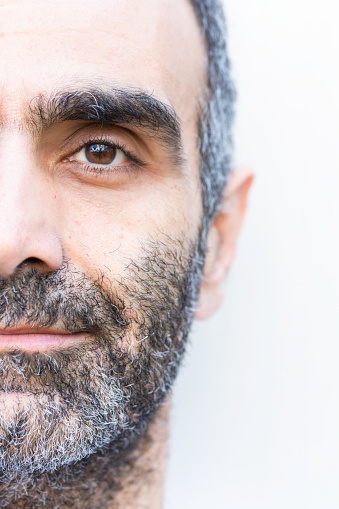 Half portrait of gray bearded man smiling and looking at camera.