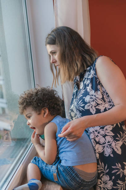 istock Mother carrying his son while looking through the window 1324939693