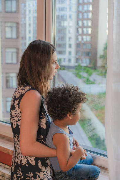 istock Mother carrying his son while looking through the window 1324939797