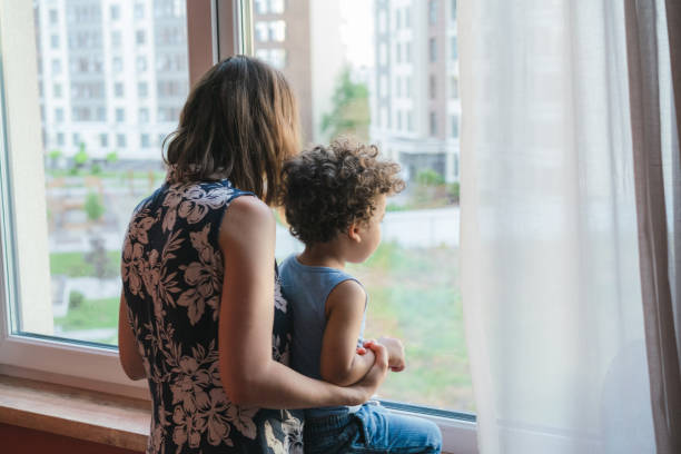 istock Mother carrying his son while looking through the window 1324940341
