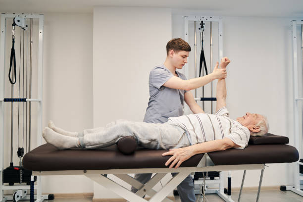 istock Orthopedist helping old man on couch in raising right arm 1324940568