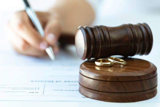 Divorce Process Weeding rings and  gavel with a person signing a contract in the background. Representing justice steps of divorce process. divorce stock pictures, royalty-free photos & images