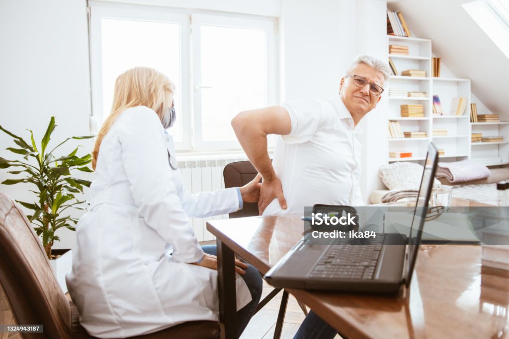 Patient complains to the doctor of kidney pain Middle-aged man being examined by a female doctor in a doctor's office. Patient complains to the doctor of kidney pain. Kidney - Organ Stock Photo