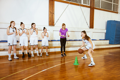 Basketball girls team ready for training. Exercise game with a ball on a basketball court.