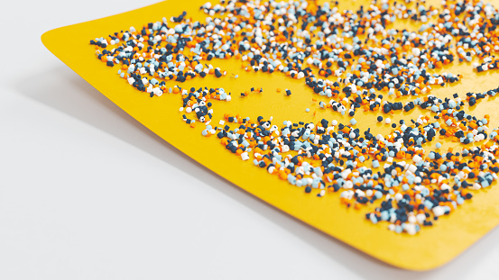Many small plastic beads on a yellow tray
