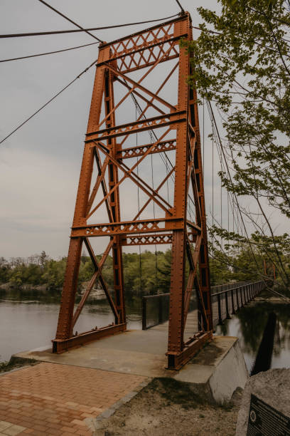 istock Iron rung bridge crossing a river on a cloudy afternoon. 1324950512