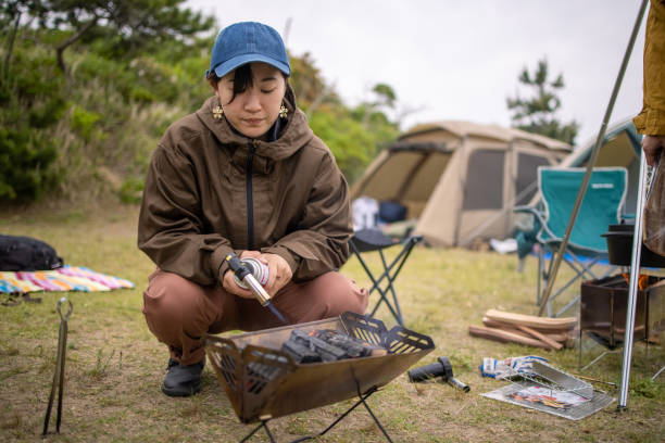 bbqのための薪を点灯若い女性 - キャンプ　準備 ストックフォトと画像