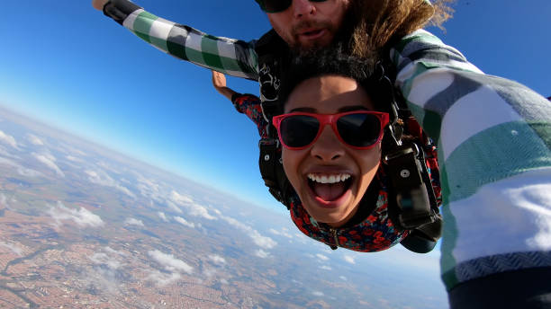 Beautiful black woman practicing skydiving. Beautiful black woman practicing skydiving. Tandem jump with selfie image. paragliding stock pictures, royalty-free photos & images