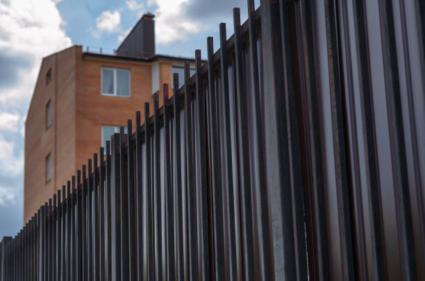 istock Apartments behind a high fence against a blue sky with clouds. T 1324961882