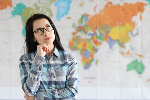 Portrait of pensive woman on background of world map. World travel and route planning concept