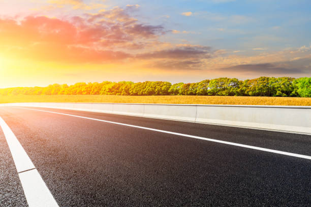 istock Empty road and ripe wheat fields at sunrise. 1324967392