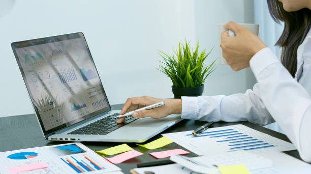 istock A businessman studying statistics and holding a graph document by hand An office worker stood near the desk with a laptop. Man pointing finger 1324967948