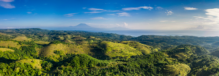Aerial drone panoramic view of the lush hilltops and valleys with scenic sea views and located on the island of Nusa Penida in Bali in Indonesia.