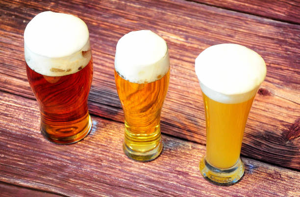 trzy różne szklanki z trzema różnymi rodzajami lekkich piw stoją w rzędzie na drewnianym stole. - draught beer variation three objects zdjęcia i obrazy z banku zdjęć