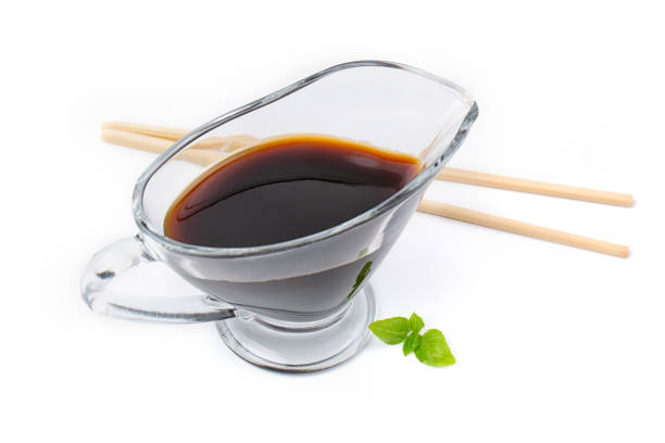 Soy sauce in a glass saucepan, isolated on a white background.