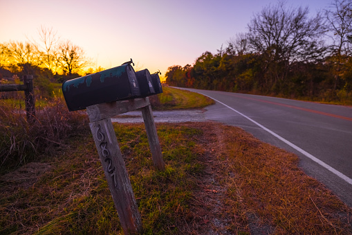 Country mailboxes road with fall colors, golden sunset with purple clouds during autumn