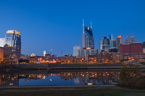 Nashville at Dusk with Beautiful Sky and Water. Downtown Nashville skyline with a beautiful pink, orange, and blue sunset, with the blue and pink of the sky reflected on the Cumberland River.