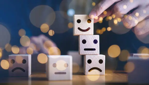 Photo of Businessman hand holding touching smile face or happy face which print screen on wooden cube block, Business service rating , Satisfaction concept.Selection & Choosing emotion or mood concept.