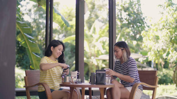 istock Smiling female friends making coffee at table in backyard. 1324991668