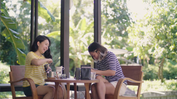 istock Smiling female friends making coffee at table in backyard. 1324991670