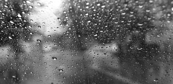 Raindrops on car windshield during rainy season.