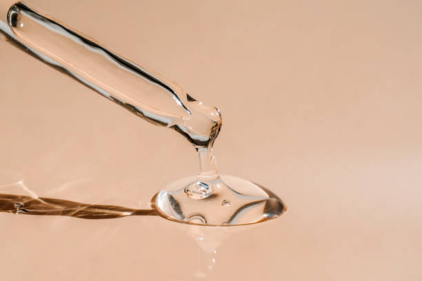 A drop of cosmetic oil falls from the pipette A drop of cosmetic preparation falls from a pipette on a beige background . Perfect for showcasing your product. Front view. face serum stock pictures, royalty-free photos & images