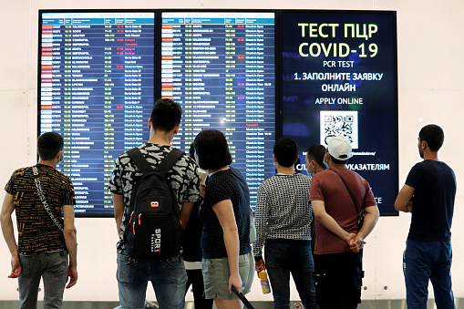 Moscow, Russia​ -​ June 2021: People looking at departure board in Domodedovo airport terminal in Moscow. Warning about safety measures during the covid-19 coronavirus pandemic