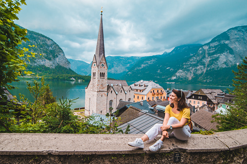 woman with backpack sitting and enjoying the vie of hallstatt austria summer travel concept