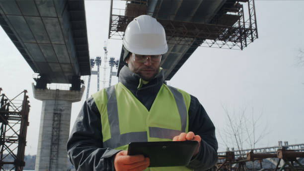 mężczyzna używający tabletu na placu budowy mostu - draft sports zdjęcia i obrazy z banku zdjęć