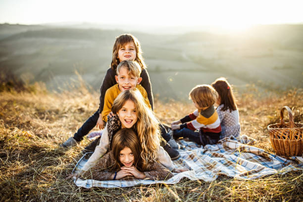 istock Happy kids making human pyramid on picnic in autumn day. 1324997841