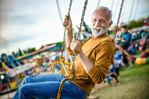istock Happy senior man having fun while riding on chain swing at amusement park. 1324999446