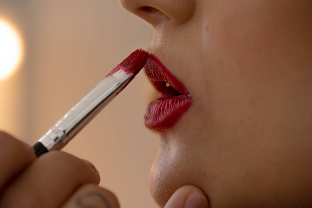 Close up lipstick applied with small make up brush to lips