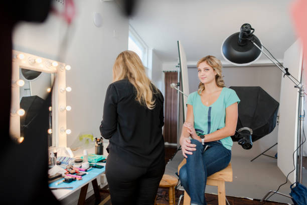 istock Wide shot model sitting on stool backstage with make up artist 1325002920