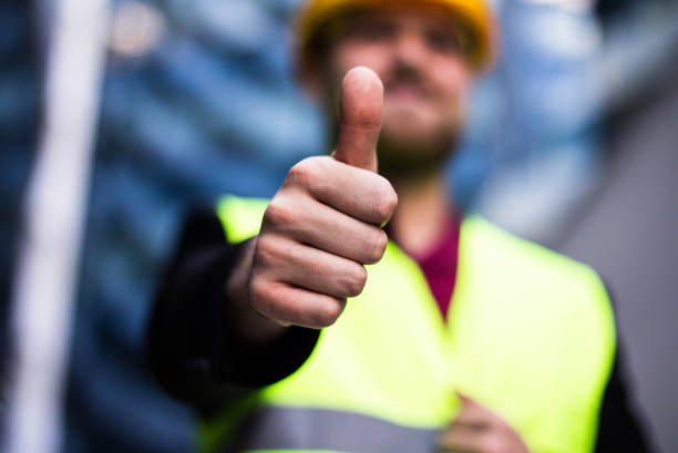 Smiling engineer standing on the street. Cloe up. Thumb up.