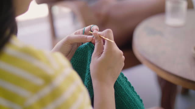 Young woman crocheting at home.