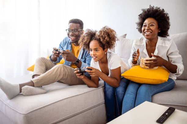 famiglia sorridente seduta sul divano insieme a giocare ai videogiochi - video game family child playful foto e immagini stock
