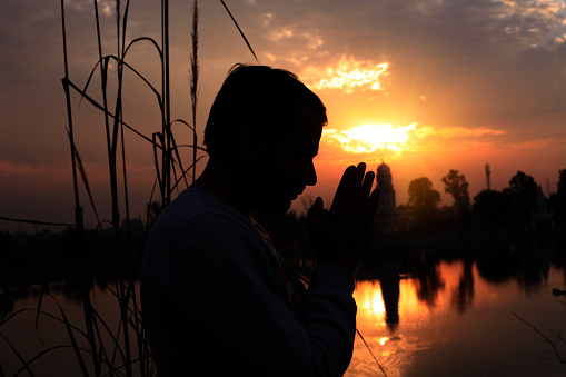 Young men wishing to god near temple during sunset time.
