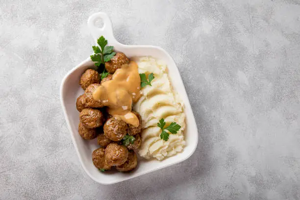 Photo of Traditional swedish meatballs with creamy sauce and mashed potatoes on gray background top view copy space for text